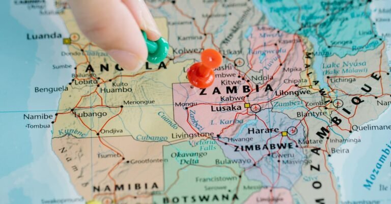 Close-up of a hand placing pushpins on a map of Africa, highlighting various locations.